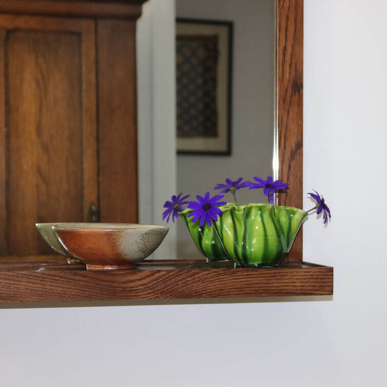 Detail of custom made oak shelf mirror with ceramics and flowers